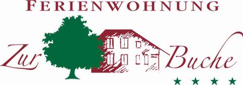 A logo for a holiday apartment called "Zur Buche". It features a house with a tree and three stars.