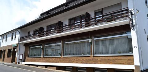 Een modern gebouw met meerdere verdiepingen en grote ramen. De façade is bekleed met bruine bakstenen en er zijn balkons in het bovenste gedeelte.