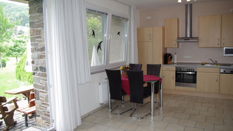 Modern kitchen with a dining area and a view of the garden. Bright windows and an inviting ambiance create a friendly atmosphere.