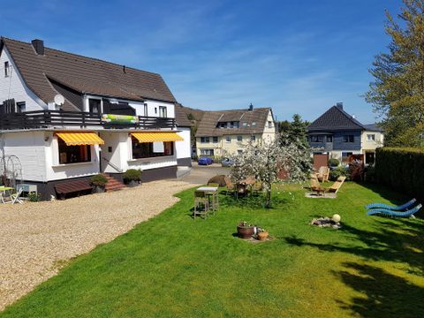 Een mooi appartementencomplex met een verzorgde tuin. Op de achtergrond zijn er meer woonhuizen te zien.