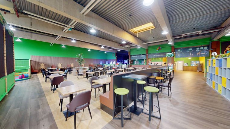 Ein modernes Restaurant mit bunten Wänden und vielen Tischen. Der Raum ist hell und einladend, ideal für gemütliche Treffen.