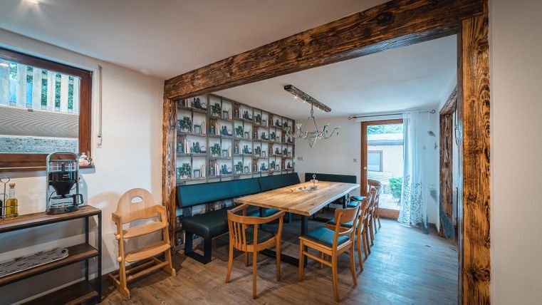 Een gezellige eetruimte met een grote houten tafel en houten stoelen. Aan de muur hangen verschillende schilderijen die een uitnodigende sfeer creëren.