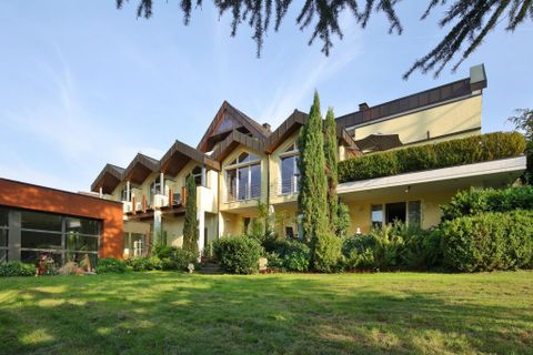 Een modern huis met een verzorgde tuin en grote ramen. De architectuur is aantrekkelijk en combineert houten en glaselementen.