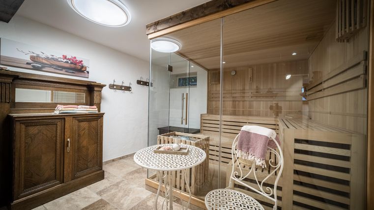 Een elegante wellnessruimte met een sauna en een kleine tafel. De kamer is modern en goed verlicht, ideaal om te ontspannen.