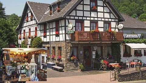 Ein traditionelles deutsches Gasthaus mit einem Fachwerkstil und blühenden Pflanzen. Im Inneren ist eine gemütliche Einrichtung zu sehen.
