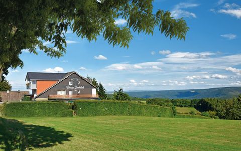 A picturesque hotel on a meadow with a beautiful view of the hills. The clear blue sky and the green landscapes create a peaceful atmosphere.