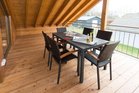 Een mooie eetruimte op een veranda met een tafel en zes stoelen. De houten vloeren en de open ramen creëren een uitnodigende sfeer.