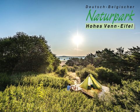 Een prachtig uitzicht op het natuurpark Hohes Venn-Eifel met een groene tentenlandschap. De zon gaat aan de horizon op en verlicht de omgeving.