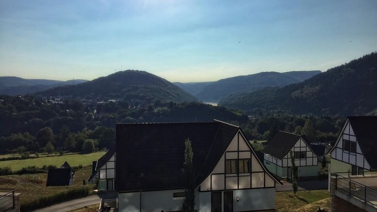 A picturesque landscape with gentle hills and a clear sky. In the foreground, modern houses can be seen.