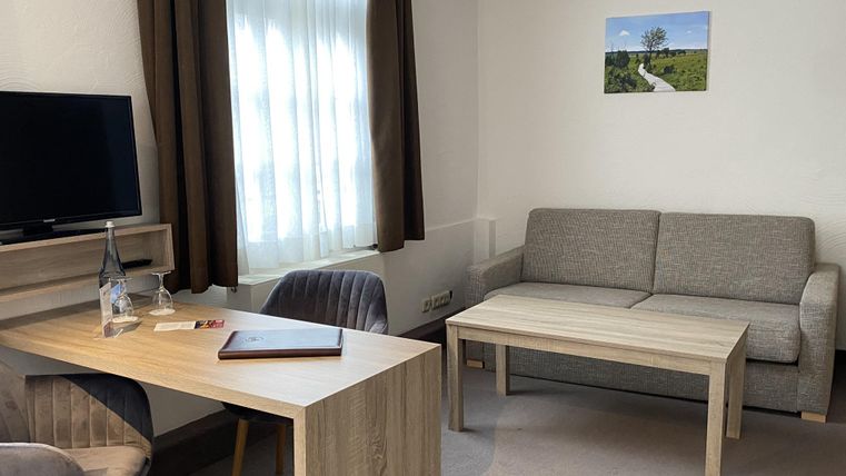 A modern room with a sofa, a table, and a television. Rays of light are streaming through the window and a picture is hanging on the wall.