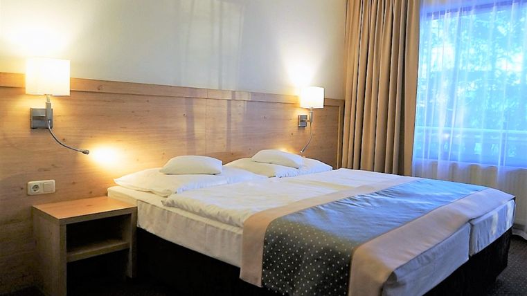 A cozy room with two beds, a desk, and a television. The ambiance is simple and inviting, ideal for a relaxing stay.
