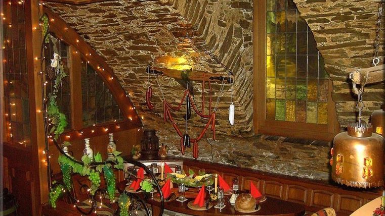Ein gemütliches Kellerrestaurant mit Steinwänden und dekorativen Lichtern. Der Tisch ist festlich gedeckt mit roten Servietten und verschiedenen Speisen.