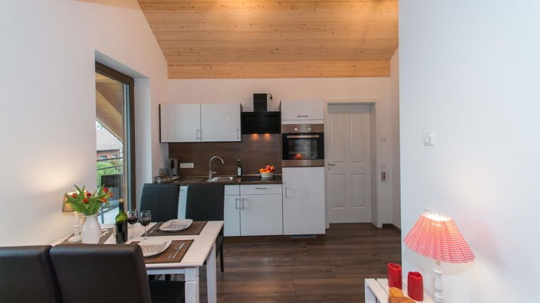 Moderne keuken met elegante inrichting en houten plafond. Een uitnodigende eetruimte met een tafel en stoelen.