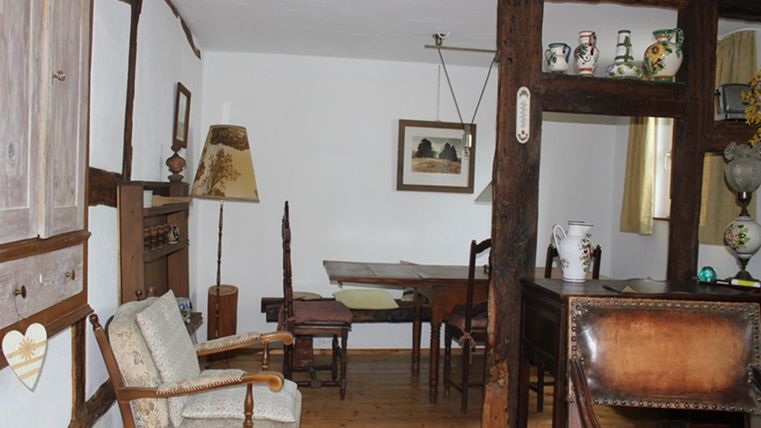 A traditional room with wooden decor and antique furniture. The room contains a table, chairs, and decorative items.