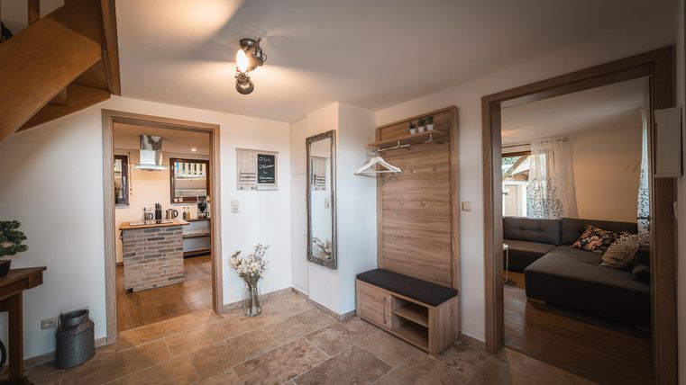 Een uitnodigende entree met een helder ontwerp. Links bevindt zich een open keuken en rechts een gezellige woonkamer.