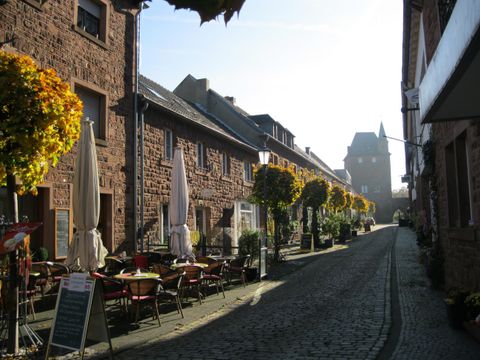 Een charmante straat met historische gebouwen en bloeiende planten. Gezellige tafels nodigen uit om te blijven zitten.