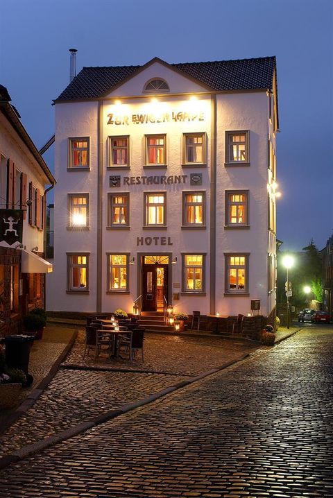 A charming hotel with a restaurant on a quiet street. The building is brightly lit and has a cozy, inviting feel.