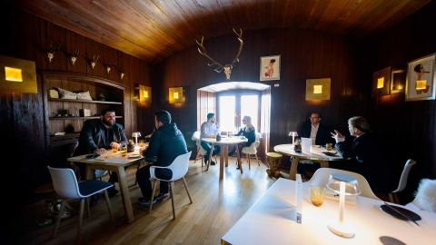 A cozy dining room with a wooden ceiling and antique decorations. Guests sit at tables and enjoy their meals in an inviting atmosphere.