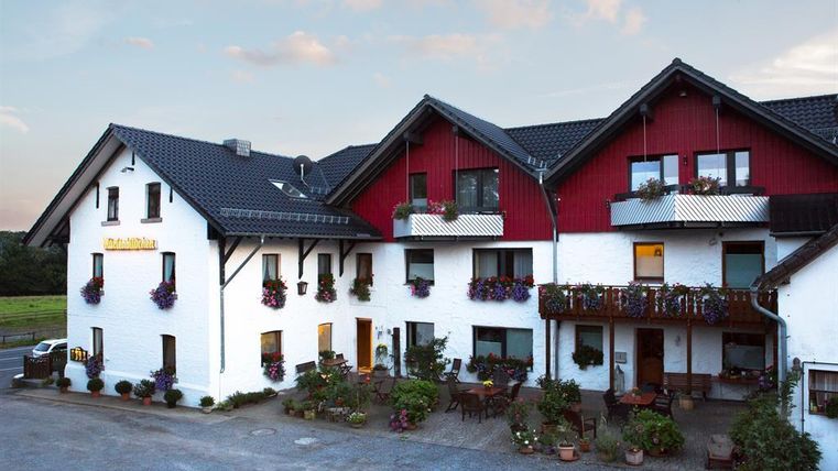 A charming inn with a red and white facade and blooming flowers. The outdoor area invites you to relax.