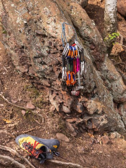 A climbing area with a rock and climbing equipment. A climbing shoe is lying next to it.
