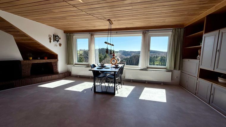 Een lichte kamer met houten plafond en grote ramen. Het uitzicht op het landschap is prachtig.