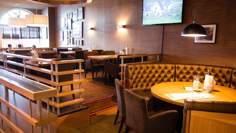 A cozy restaurant with a modern interior. The seating is comfortable, and there is a television on the wall.