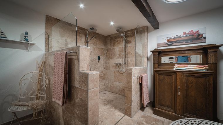 Een moderne badkamer met een dubbele open douche en stijlvolle tegels. Houten en metalen accenten geven de ruimte een gezellige sfeer.