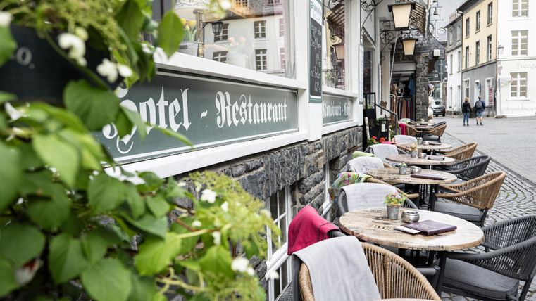 Ein gemütliches Restaurant mit Außenterrasse in einer hübschen Straße. Tische und Stühle sind bereit für Gäste, um die Umgebung zu genießen.