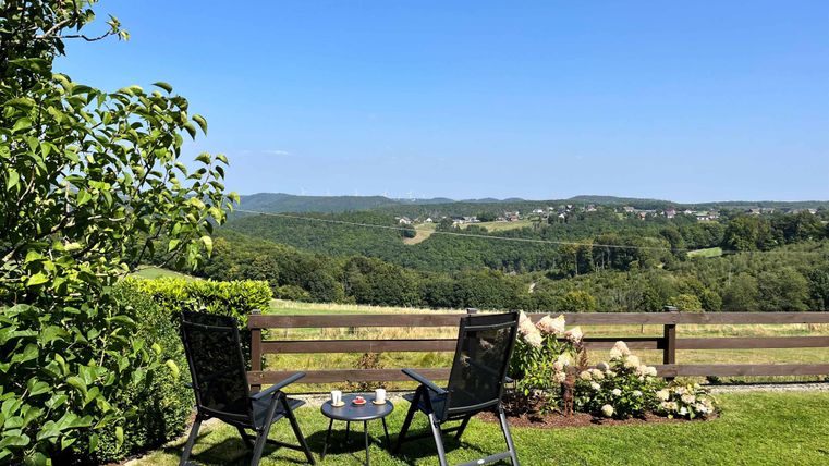 A beautiful view of green hills from a terrace. Two chairs are ready for relaxed moments in nature.