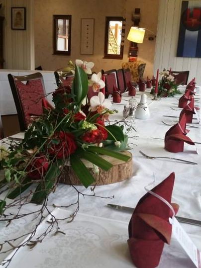 Ein festlich gedeckter Tisch mit roten Servietten und einem Blumenarrangement. Die Umgebung wirkt gemütlich und einladend.