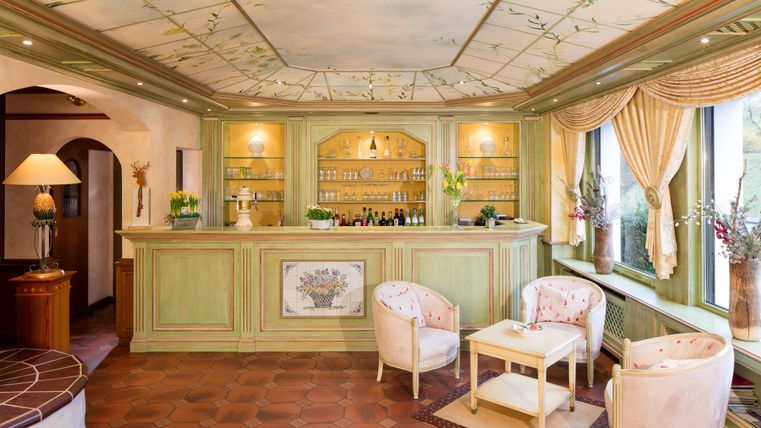 Een uitnodigende ontvangsthal met een groene bar en elegante zitplaatsen. De ruimte is helder en smaakvol ingericht.