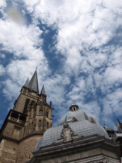 Een indrukwekkende architectuur met een hoge kerk en een opvallende koepel. De lucht is door veel wolken doorsneden.