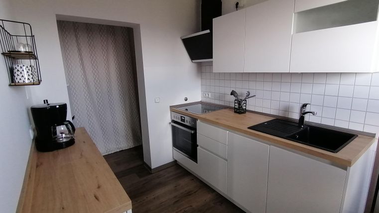 A modern kitchen with white cabinets and a wooden countertop. The room is bright and friendly designed.