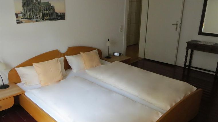 Een gezellige slaapkamer met een twijfelaar en twee kussens. Aan de muur hangt een afbeelding van een mooie kathedraal.