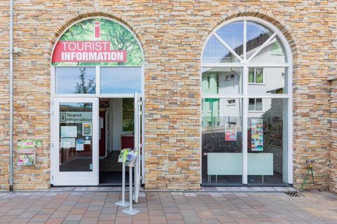 Ein Tourist-Informationszentrum mit einem einladenden Eingang. Die Fassade besteht aus hellem Stein und das Schild weist auf touristische Informationen hin.
