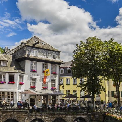 A charming café with a restaurant and hotel in a picturesque town. Blooming flowers and cozy terraces invite you to linger.