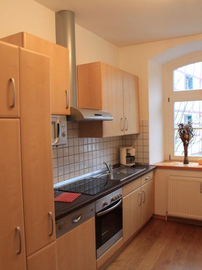 Een moderne keuken met houten kasten en een fornuis. Ze heeft een raam met uitzicht naar buiten en een gezellige sfeer.