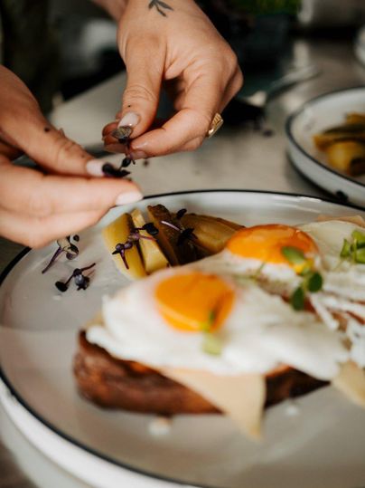 A delicious breakfast dish with scrambled eggs and bread is lovingly arranged. Fresh herbs and sides add an appealing touch to the plate.