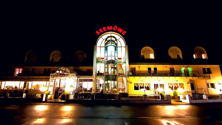 Een verlicht gebouw met de naam "Seemöwe" in de nacht. Het heeft een moderne architectuur en een uitnodigende sfeer.