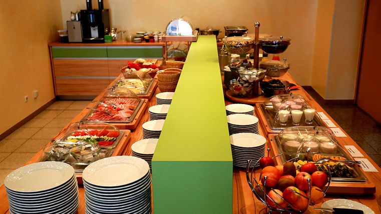 A rich breakfast buffet with fresh fruit, bread, and various dishes. The tables are neatly set and invite indulgence.