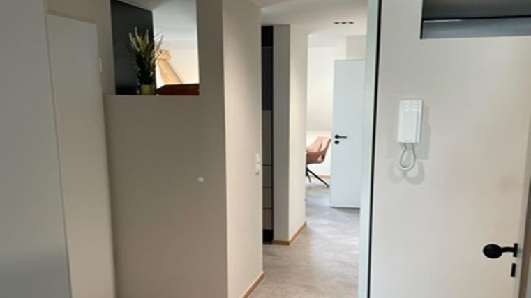 Een moderne hal met lichte muren en zachte kleuren. Het openontwerp zorgt voor een uitnodigende sfeer.