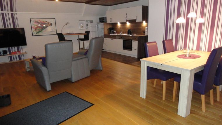 Een moderne woning met een open keuken en een gezellige woonkamer. De ruimte is goed verlicht en heeft een uitnodigende sfeer.