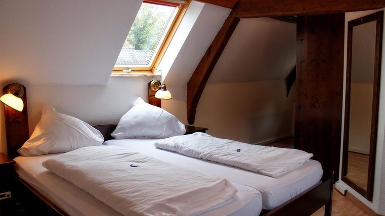 Een gezellige slaapkamer met een tweepersoonsbed en twee kussens. De kamer heeft een venster met uitzicht op de natuur en een grote spiegel.