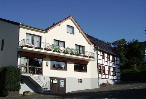 A charming building with a landscaped entrance area. The facade is friendly and inviting, with flowers on the balcony.