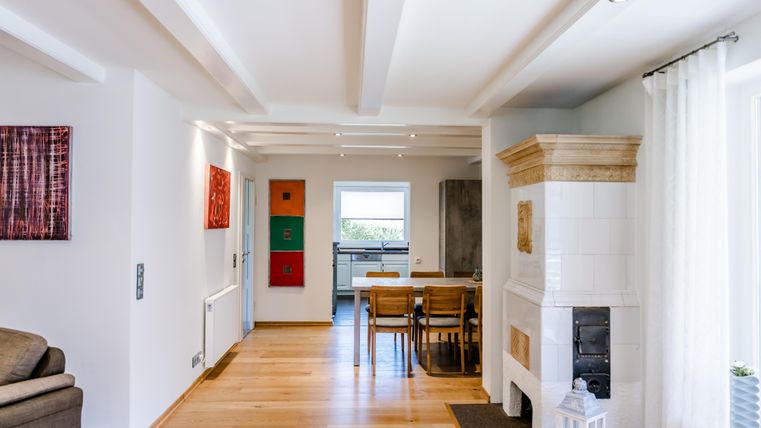 Een moderne, lichte woonkamer met houten vloeren en een open haard. De kamer is versierd met kunstwerken en een eettafel.