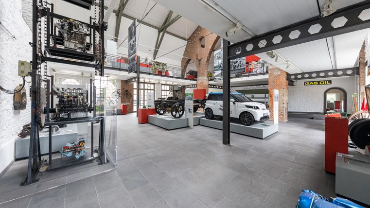 Een modern tentoonstellingsgebouw met verschillende voertuigen en machines. De ruimte is helder en open, met een industriële stijl.