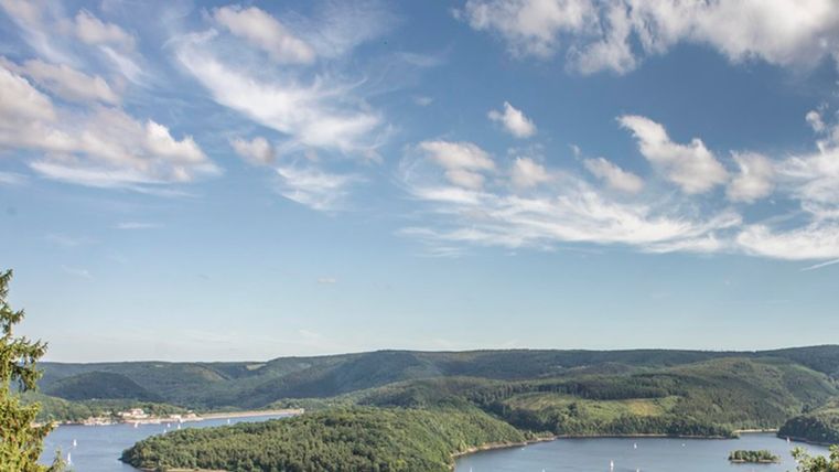 Een prachtig landschap met een rustig water en zachte heuvels. De lucht is helder met enkele wolken.