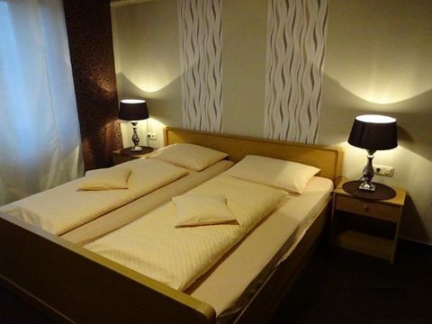 A cozy bedroom with a double bed and two nightstands. The walls are painted in soft colors, and gentle light creates an inviting atmosphere.
