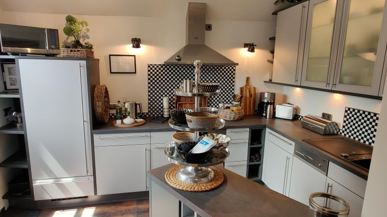 Een moderne keuken met heldere verlichting en eenvoudige meubels. Op het werkblad staan decoratieve elementen en keukengerei.