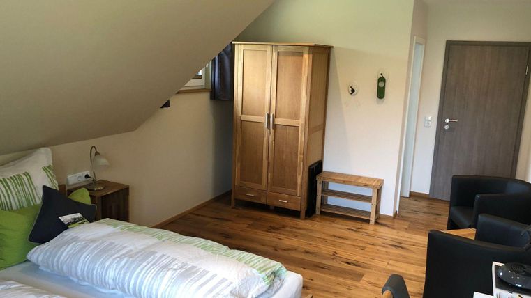 Ein gemütliches Schlafzimmer mit einem großen Bett und eleganter Holzdeko. Das Zimmer hat einen warmen Holzboden und moderne Möbel.